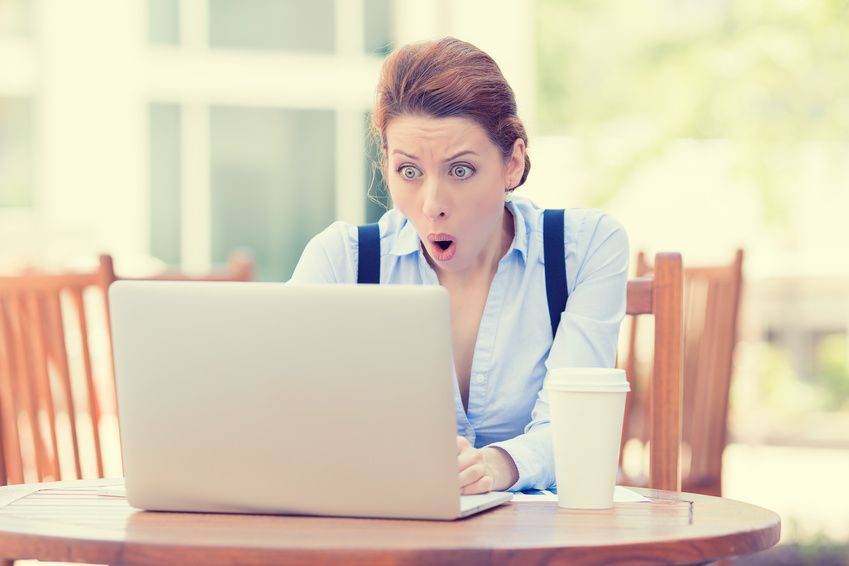 Shocked business woman using laptop looking at computer screen